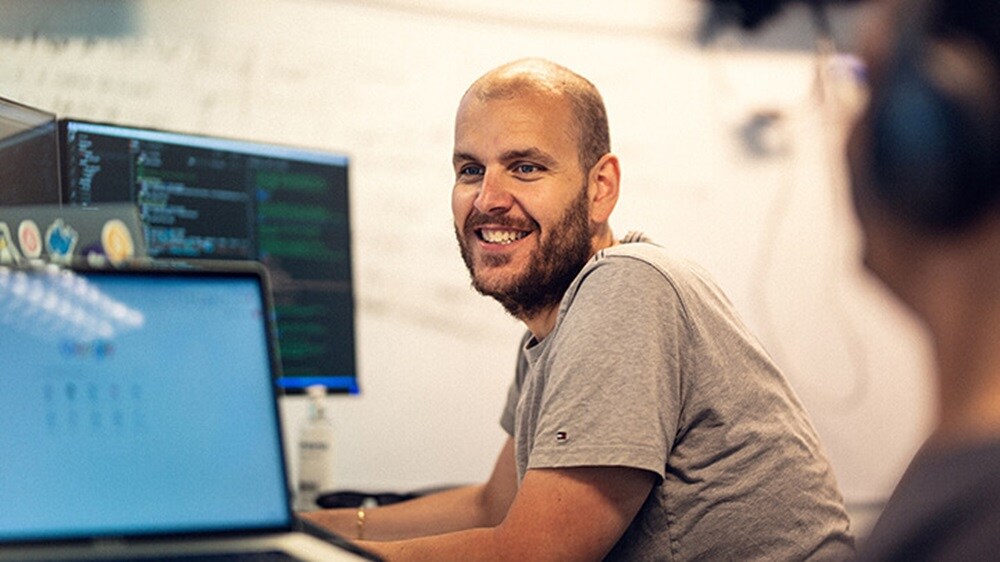 一位架构师在工作站微笑着和同行架构师交谈。