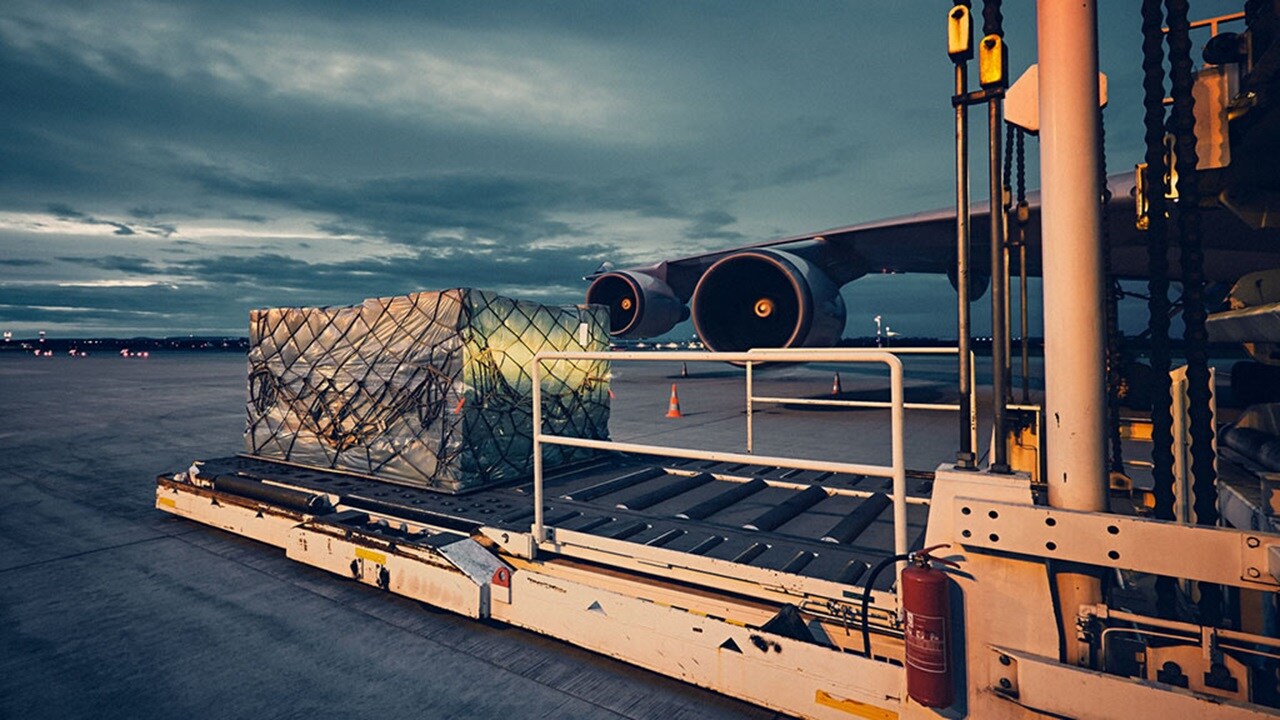 A pallet of cargo is on a conveyor belt on an airport runway