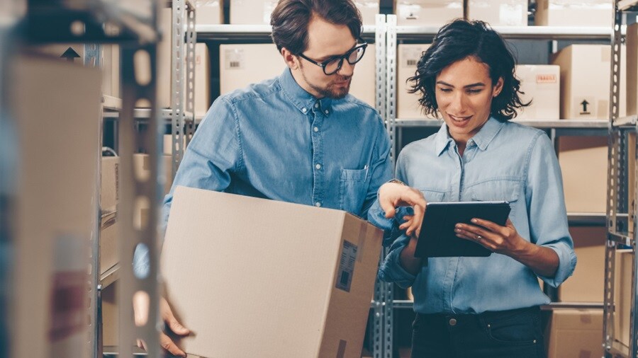 A man and a woman checking shipment logs 
